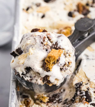 a scoop of all the cookies ice cream resting on top of the remaining ice cream