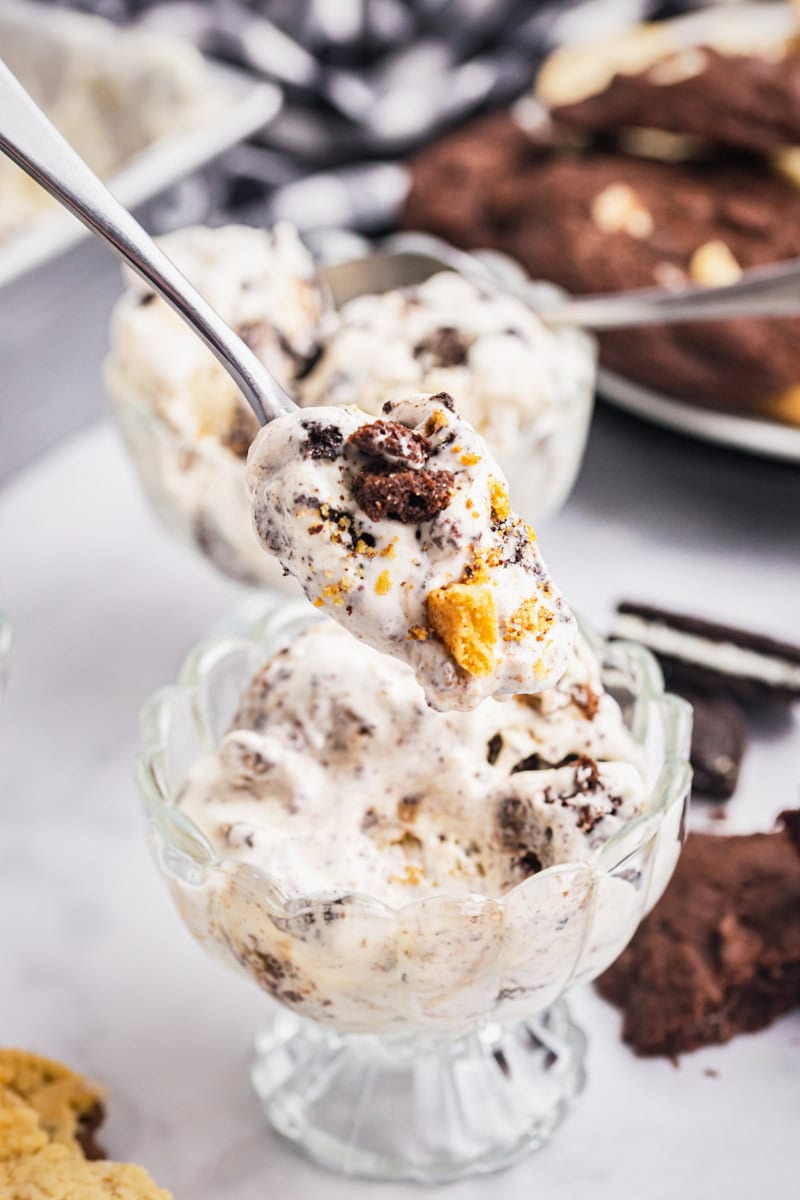a bite of all the cookies ice cream on a spoon with a bowl of ice cream in the background