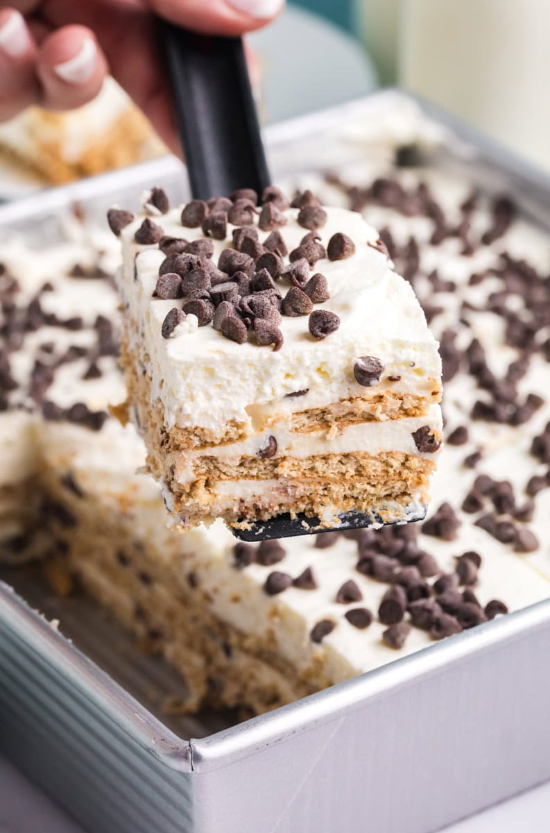 a slice of cannoli icebox cake being lifted away from the remaining cake