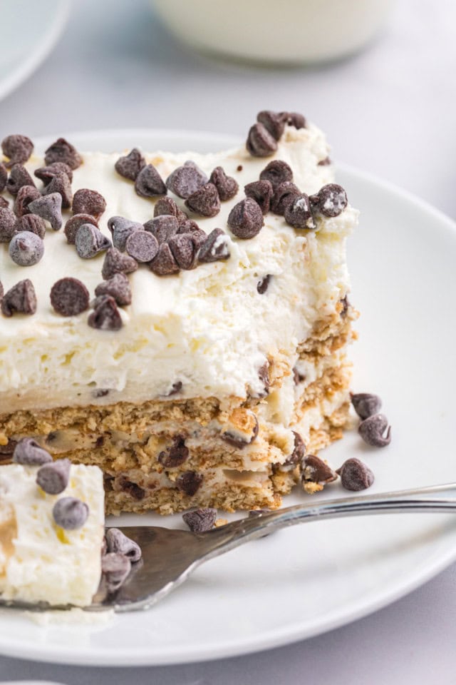 close-up view of a slice of cannoli icebox cake on a white plate with a bite on a fork