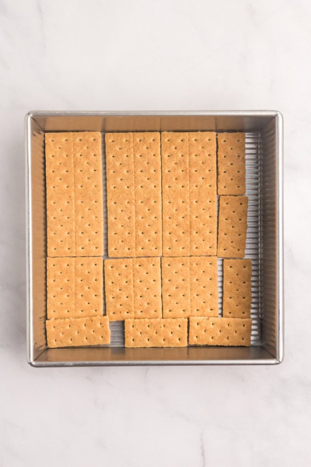 overhead view of graham crackers arranged in a single layer in the bottom of a square pan