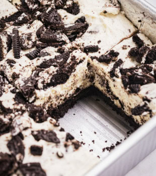 Oreo cheesecake bars in the pan with a slice missing