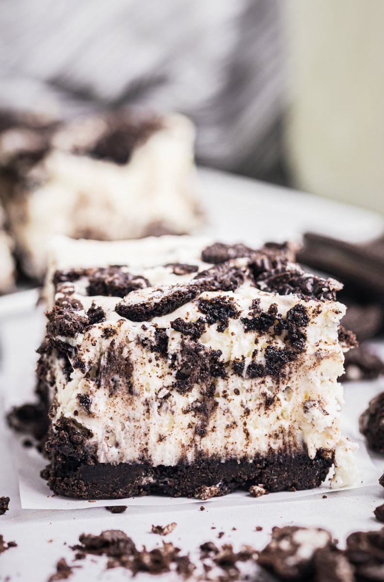 an Oreo cheesecake bar on a white surface with more bars in the background