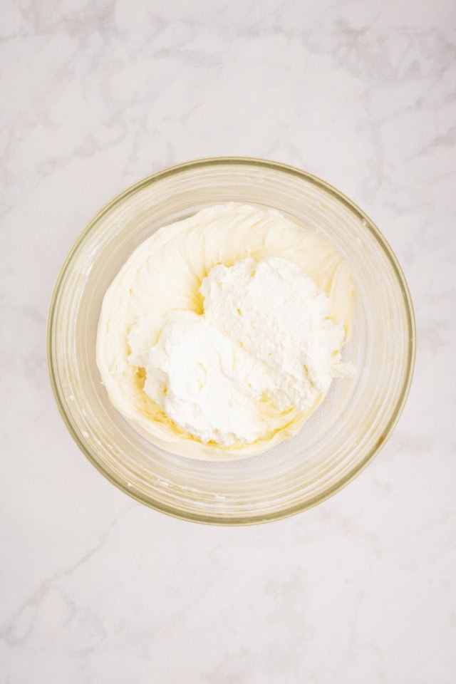 overhead view of whipped cream added to sweetened cream cheese mixture