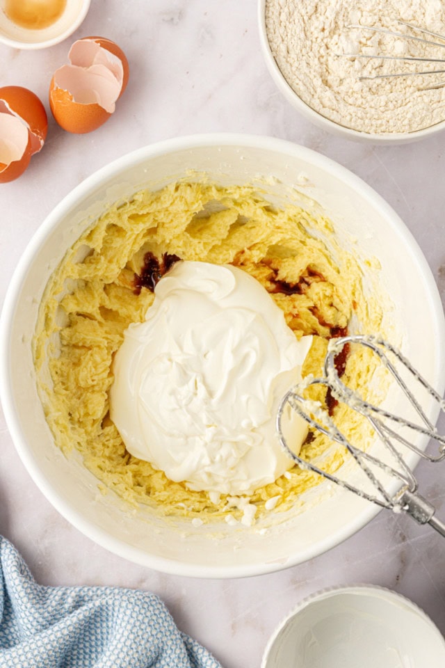 overhead view of sour cream and vanilla extract added to creamed butter, sugar, and eggs