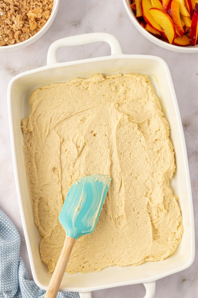 overhead view of peach coffee cake batter spread in a rectangular pan