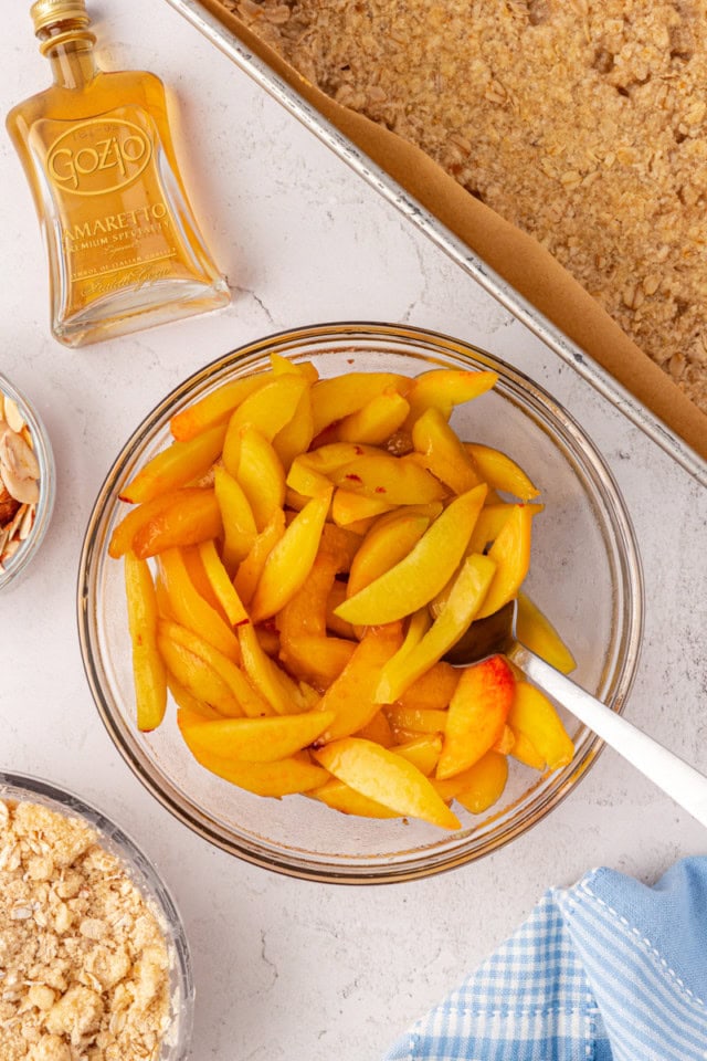 overhead view of sliced peaches tossed with Amaretto in a glass bowl