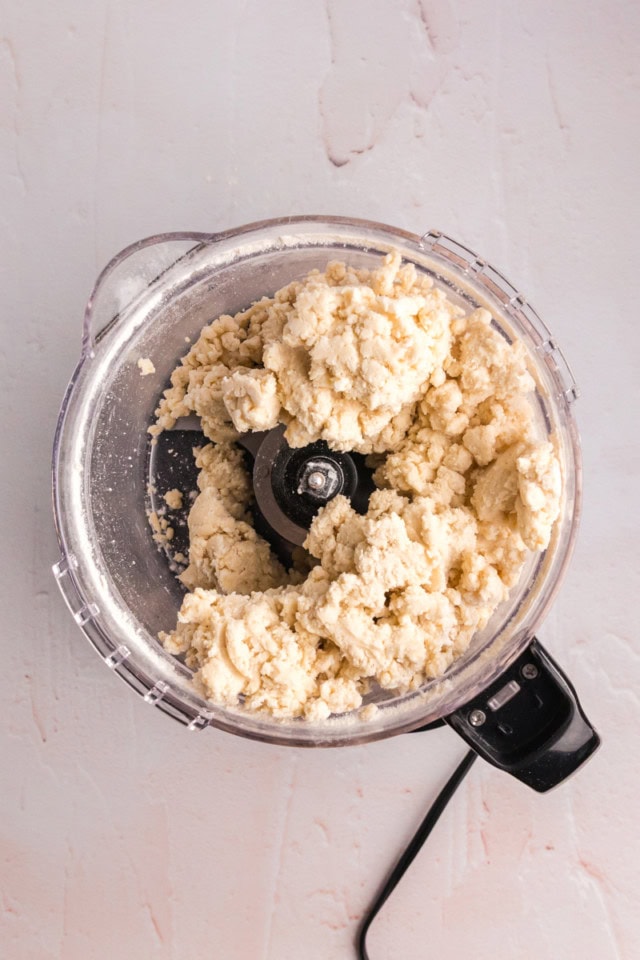 overhead view of cream cheese pastry dough in the bowl of a food processor