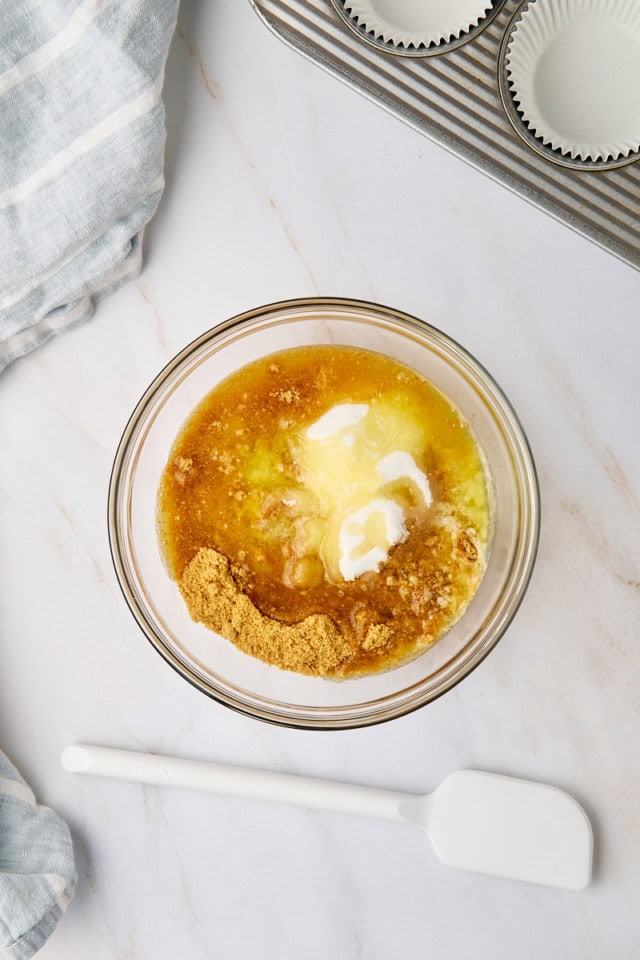 overhead view of graham cracker crumbs, sugar, and melted butter in a glass mixing bowl
