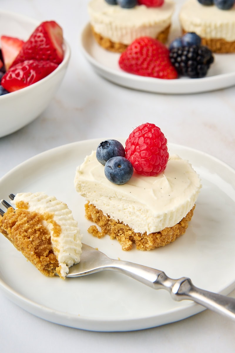 a mini no-bake cheesecake on a white plate with a bite on a fork