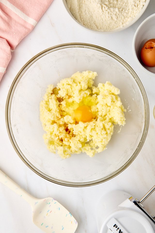 overhead view of egg added to creamed butter and sugar