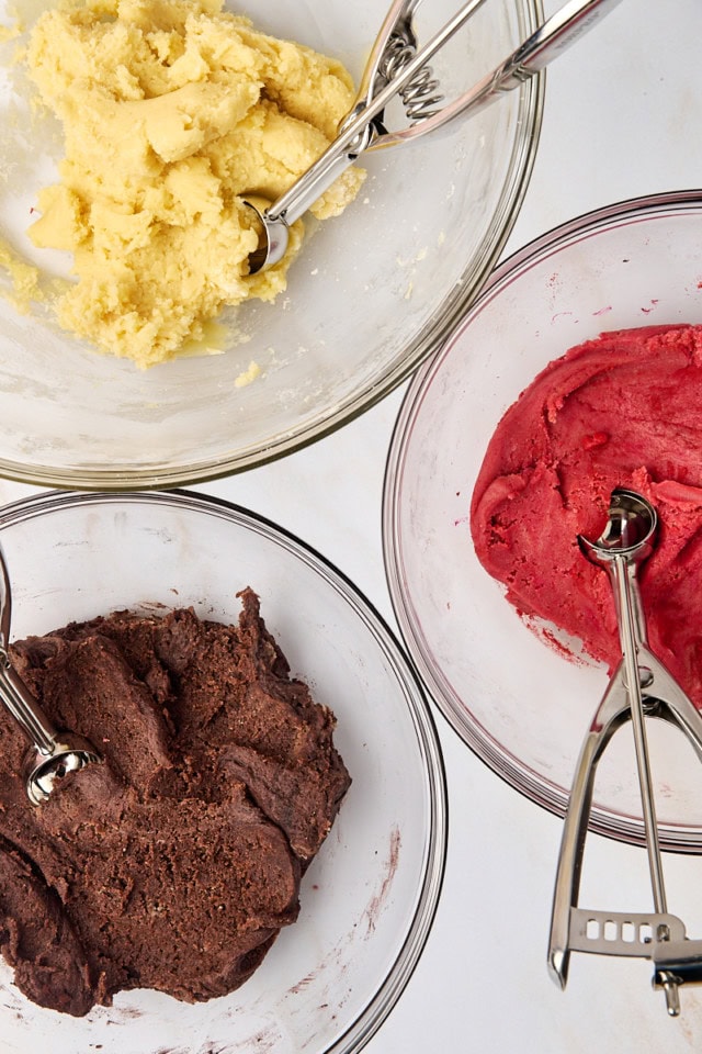 overhead view of vanilla, chocolate, and strawberry cookie doughs in glass bowls