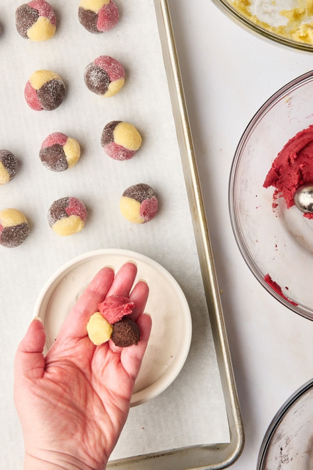 a teaspoonful of strawberry, chocolate and vanilla cookie doughs pressed together in the palm of a hand