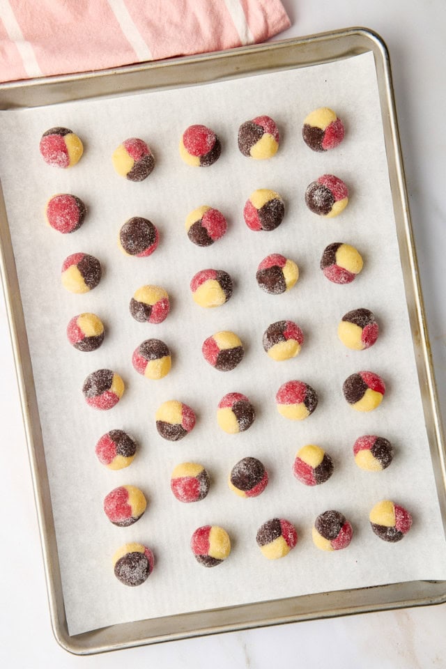 overhead view of Neapolitan cookie dough balls on a lined baking sheet ready to be chilled before baking
