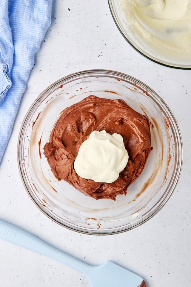 overhead view of whipped cream added to no-bake chocolate cheesecake batter