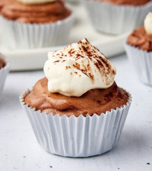 a mini no-bake chocolate cheesecake on a white surface with more cheesecakes in the background