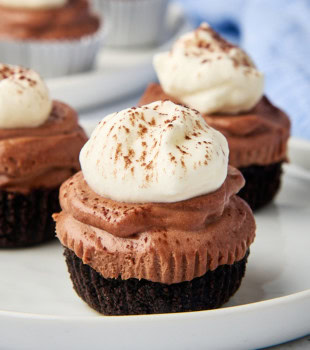 a mini no-bake chocolate cheesecake on a white plate with more cheesecakes in the background