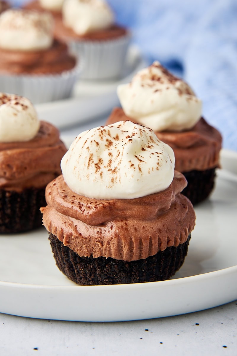 a mini no-bake chocolate cheesecake on a white plate with more cheesecakes in the background