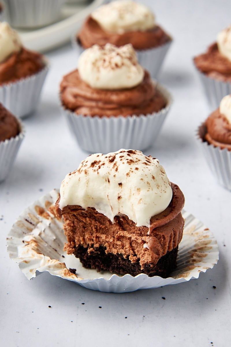 a mini no-bake chocolate cheesecake with a bite missing; more cheesecakes in the background