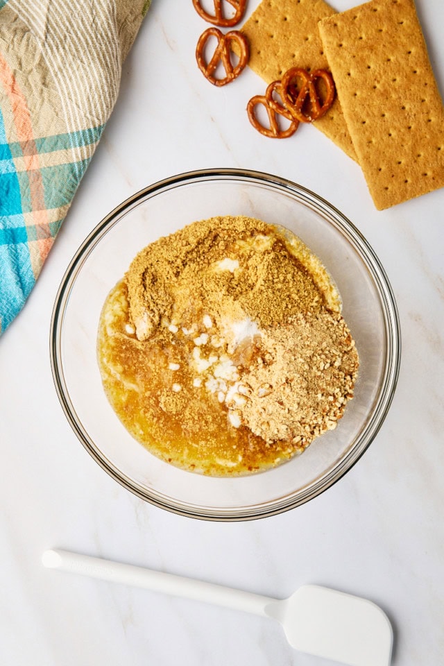 overhead view of ingredients for a graham-pretzel crust in a glass mixing bowl