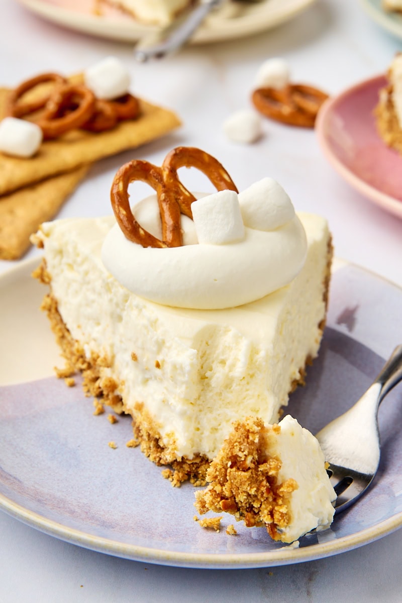 a slice of no-bake marshmallow cheesecake on a purple and white plate with a bite on a fork