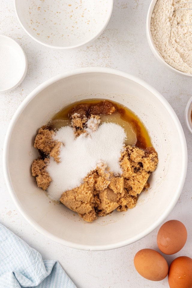 overhead view of brown sugar and sugar added to brown butter in a white mixing bowl