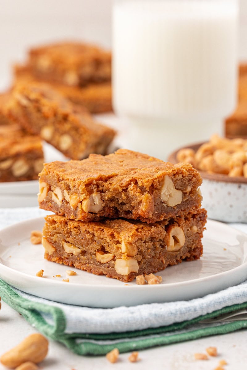 a stack of two brown butter blondies on a white plate with a bite missing from the top bar