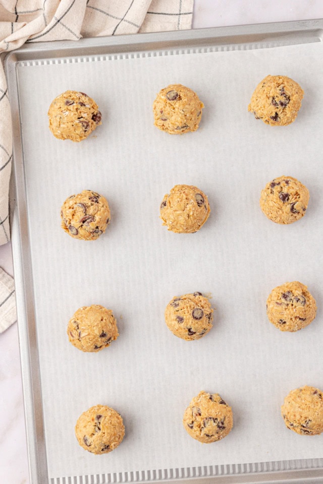 overhead view of brown sugar oatmeal chocolate chip cookie dough on a parchment-lined baking sheet