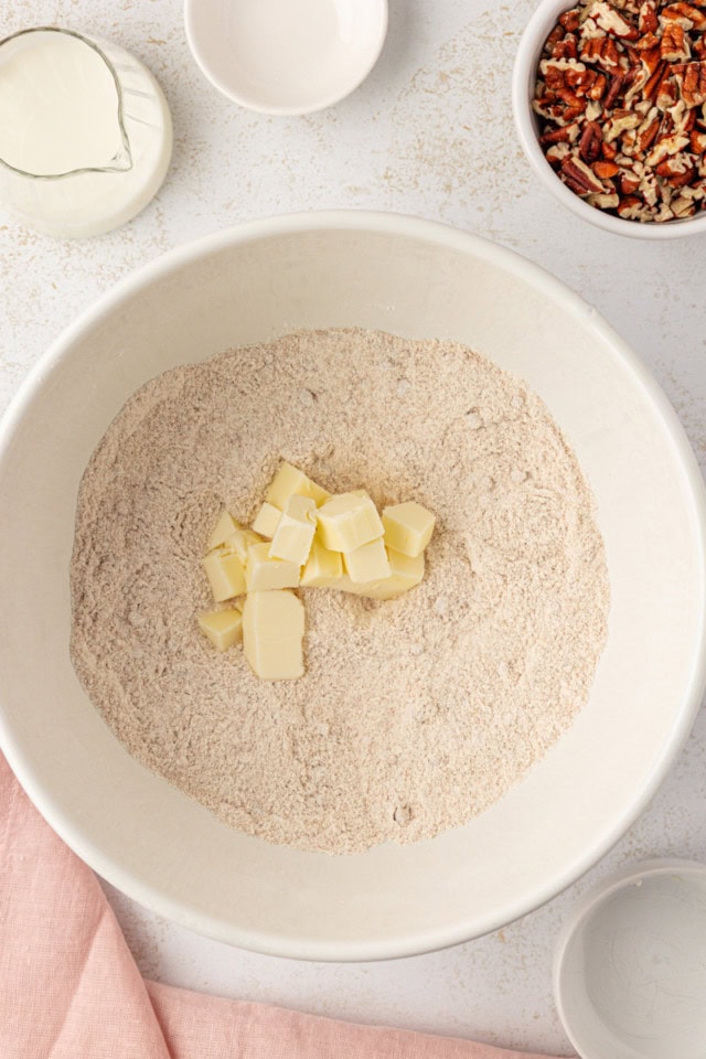 overhead view of cold, cubed butter added to dry ingredients for cobbler topping