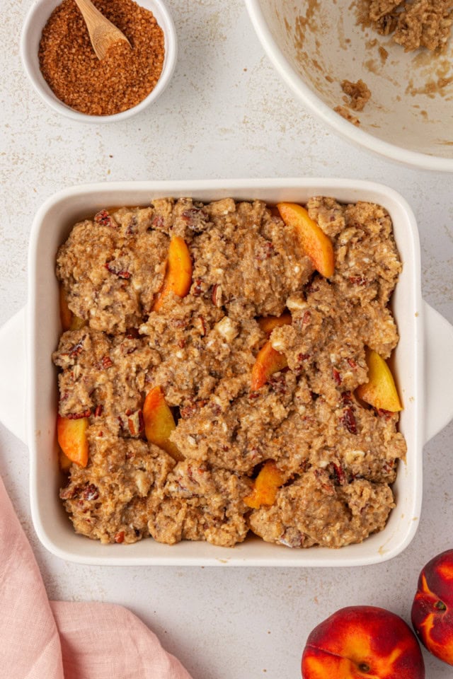 overhead view of ginger peach cobbler in a white baking dish ready to go into the oven