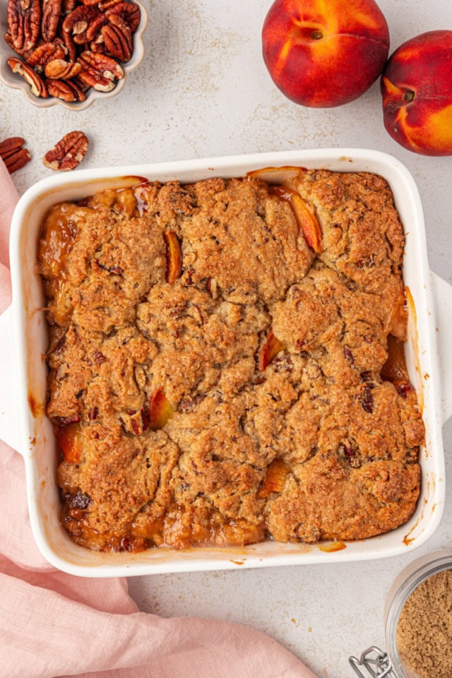 overhead view of freshly baked ginger peach cobbler in a white baking dish