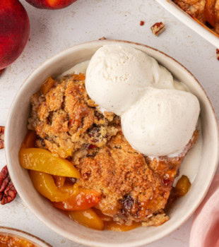 overhead view of a serving of ginger peach cobbler topped with ice cream in a bowl