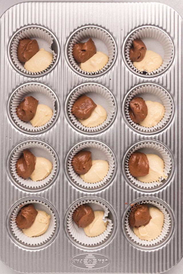 overhead view of chocolate and vanilla cupcake batters being added to lined muffin cups