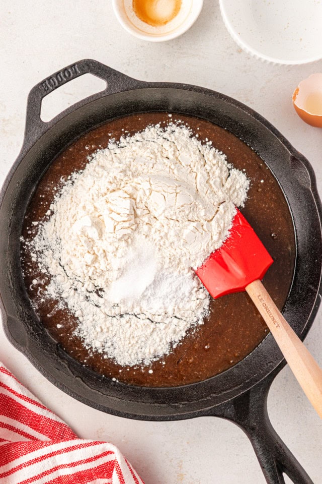 overhead view of flour, baking powder, and salt added to wet ingredients for a skillet cookie