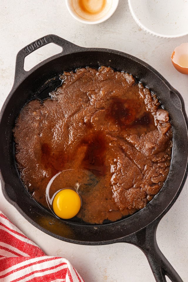 overhead view of egg and vanilla added to cooled butter and brown sugar mixture in a cast iron skillet