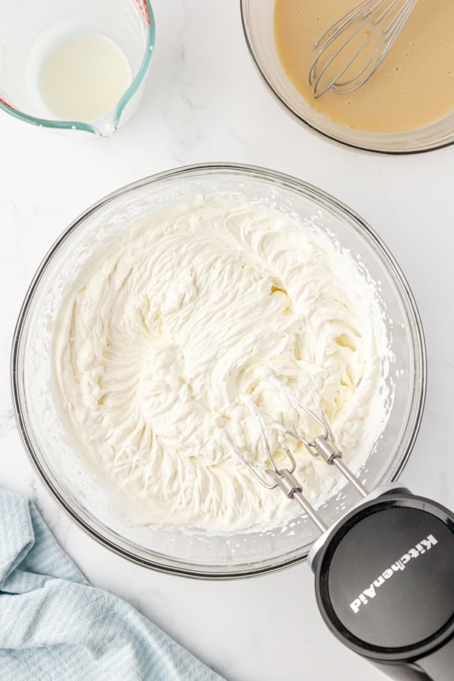 overhead view of whipped cream in a glass mixing bowl