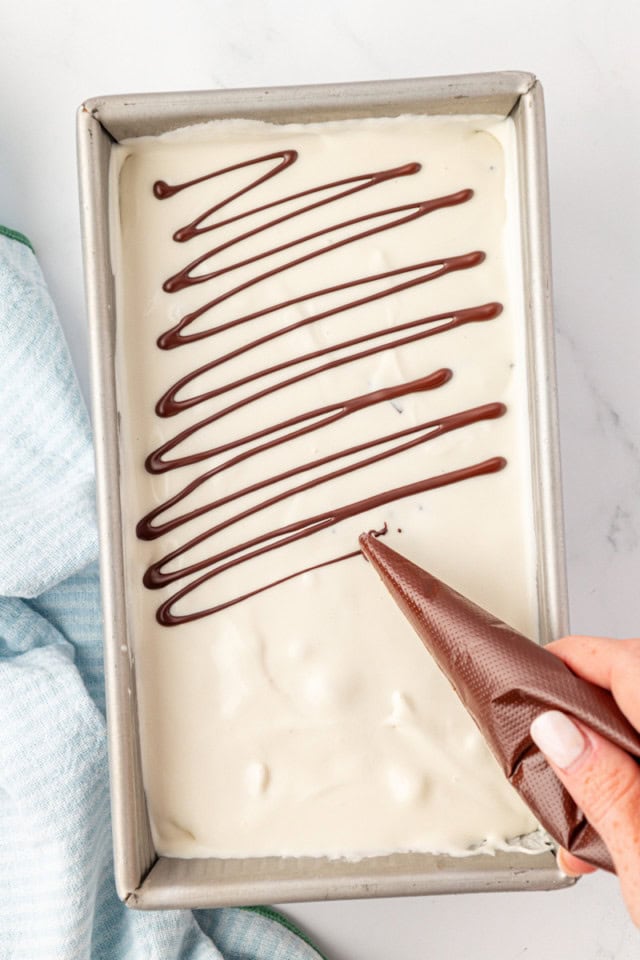 overhead view of melted chocolate being drizzled over vanilla ice cream