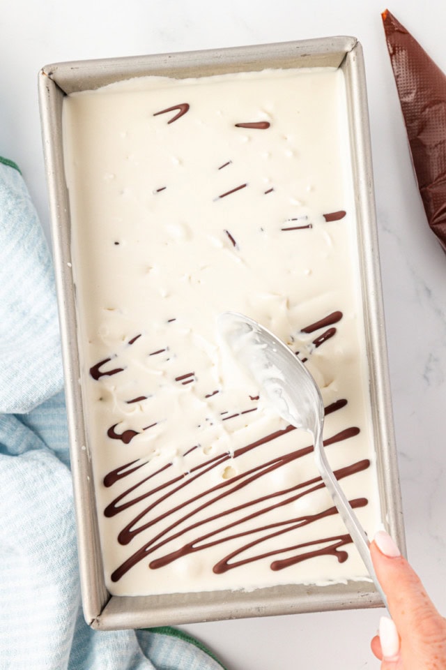 overhead view of a spoon breaking up hardened chocolate into stracciatella ice cream