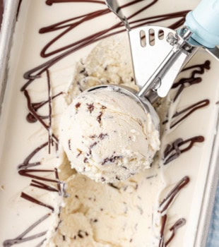 overhead view of stracciatella ice cream in an ice cream scoop resting on the remaining ice cream