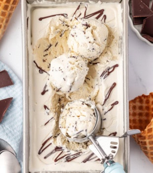 overhead view of stracciatella ice cream in a metal pan with three scoops on top