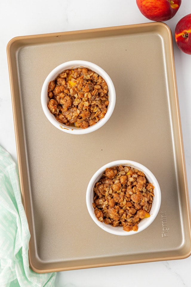 overhead view of freshly baked peach crisp for two on a baking sheet