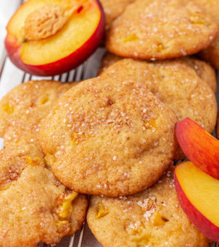 peach cookies and a few fresh peach slices on a wire rack