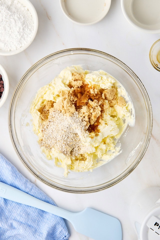 overhead view of brown sugar, ground oats, vanilla extract, and salt added to beaten butter and cream cheese