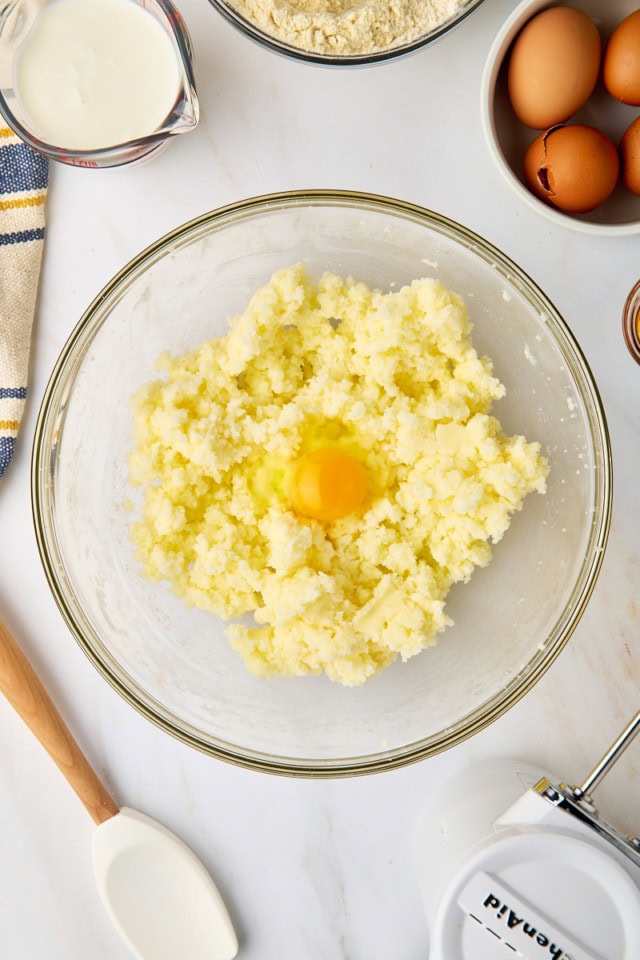 overhead view of egg added to creamed butter and sugar in a glass mixing bowl