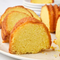 a slice of cornmeal pound cake on a white cake plate with more cake surrounding
