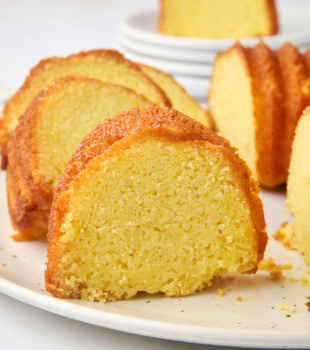 a slice of cornmeal pound cake on a white cake plate with more cake surrounding