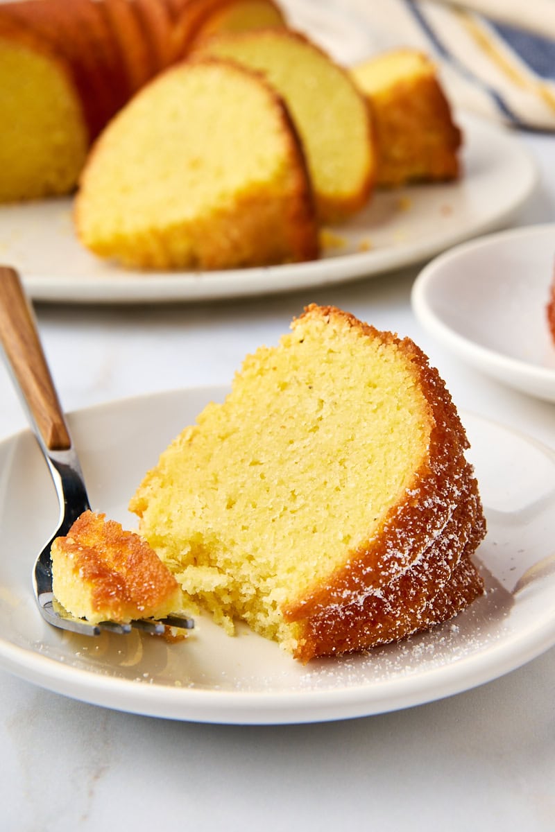 a slice of cornmeal pound cake on a white plate with a bite on a fork