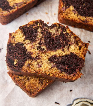 stack of two slices of marbled chocolate banana bread on parchment paper with more slices partially visible alongside