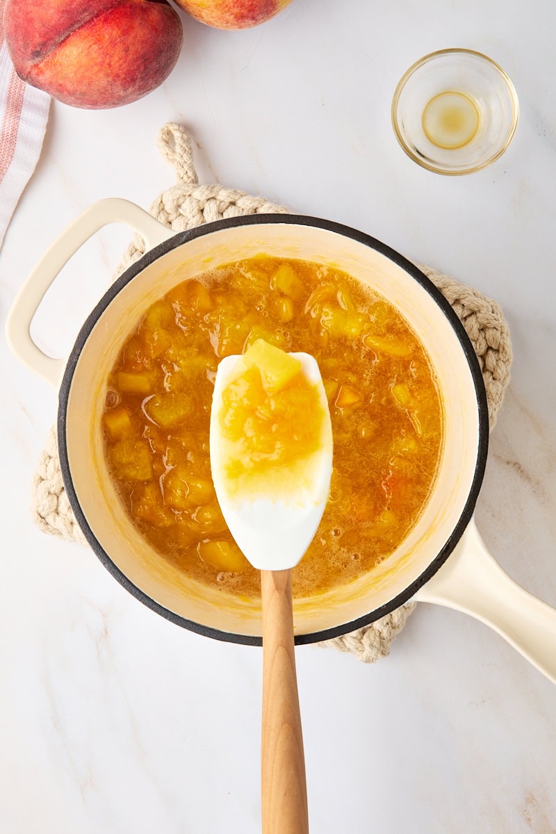 overhead view of a spoonful of peach compote over the remaining compote in a saucepan