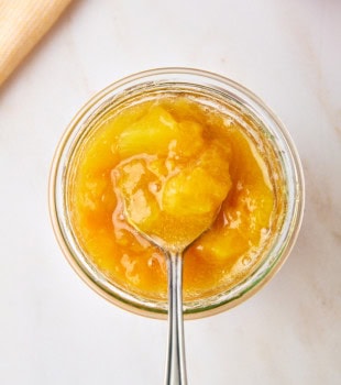 a spoonful of peach compote over the remaining compote in a glass jar